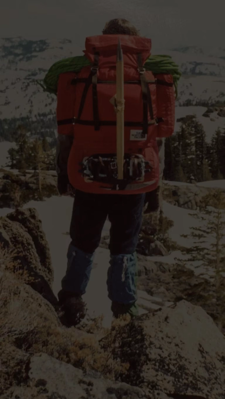 A backpacker treks through the snow-covered mountains wearing a fully packed.