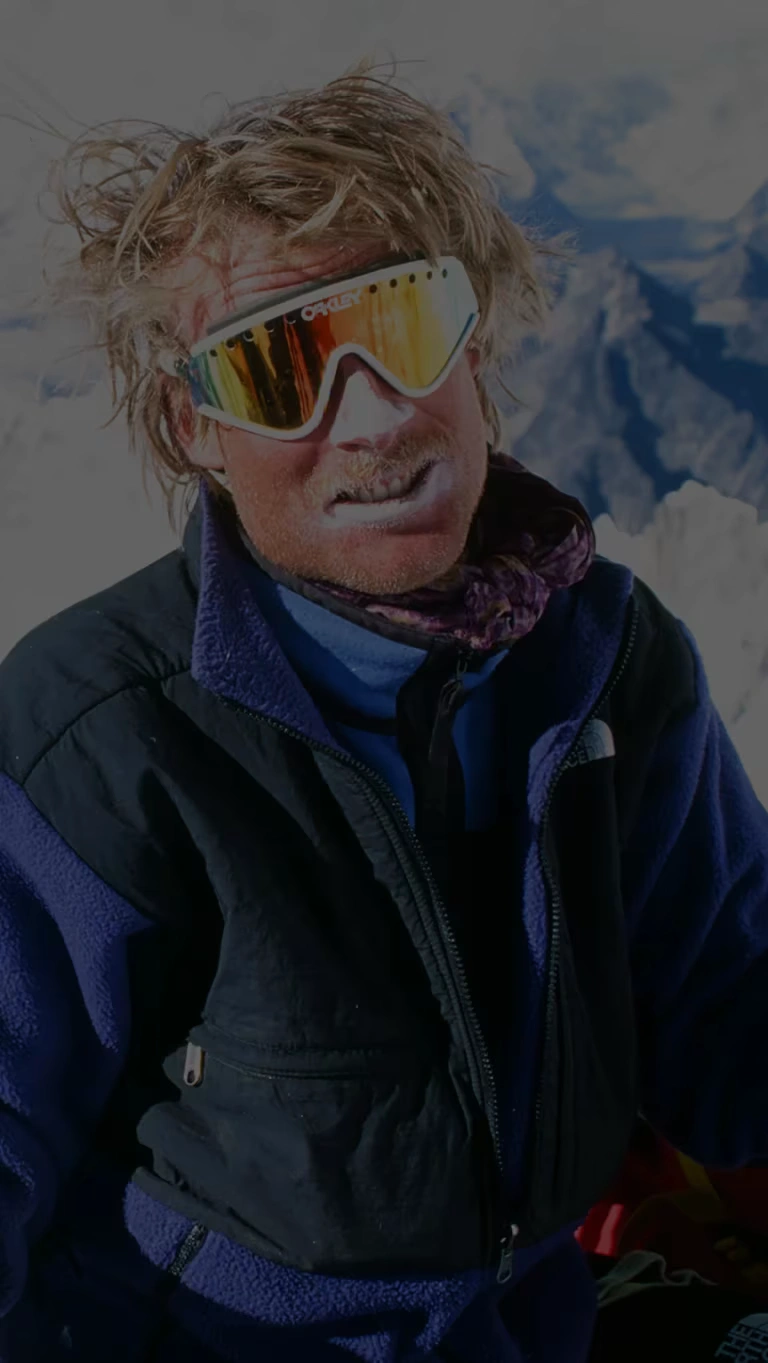 Snowboarders wearing the Denali Fleece Jacket pose with their gear in front of a snow covered peak.