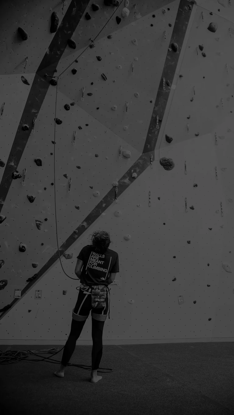 A young climber enjoys learning on an indoor rock wall.