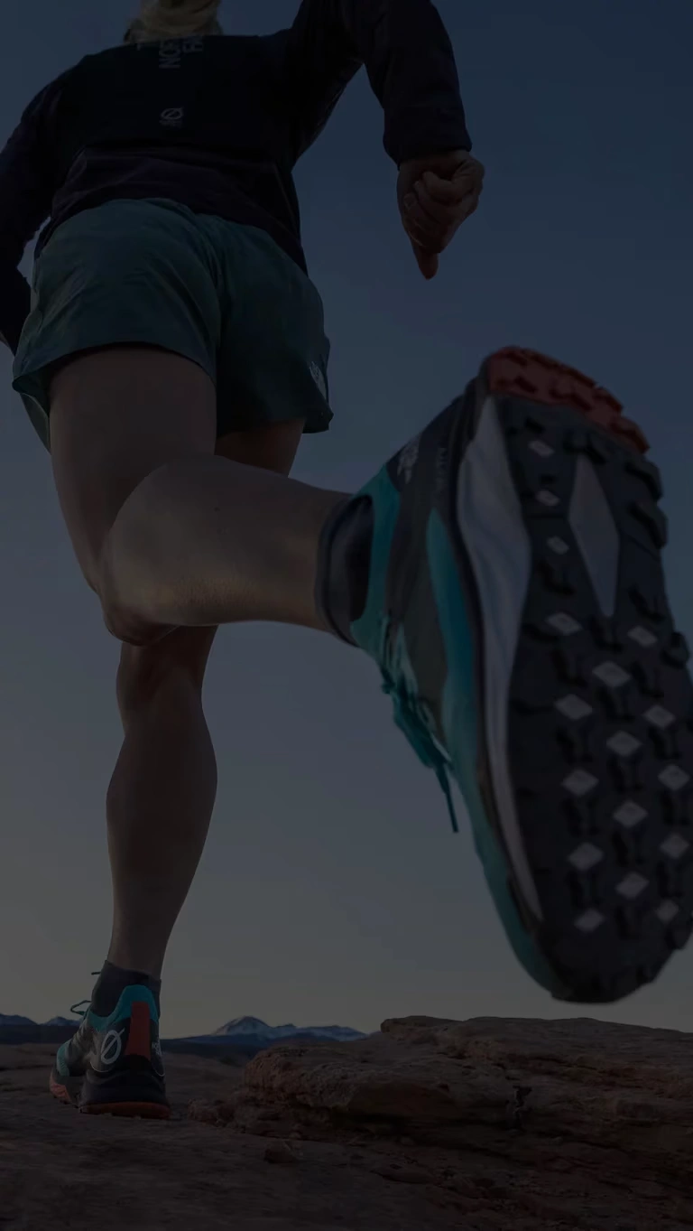 A trail runner races through a desert landscape.